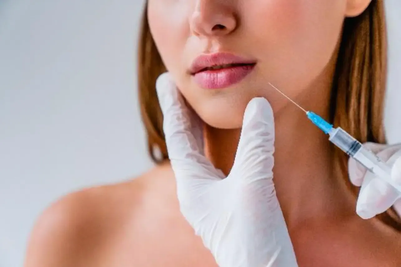Woman receiving dermal filler injection from aesthetic practitioner